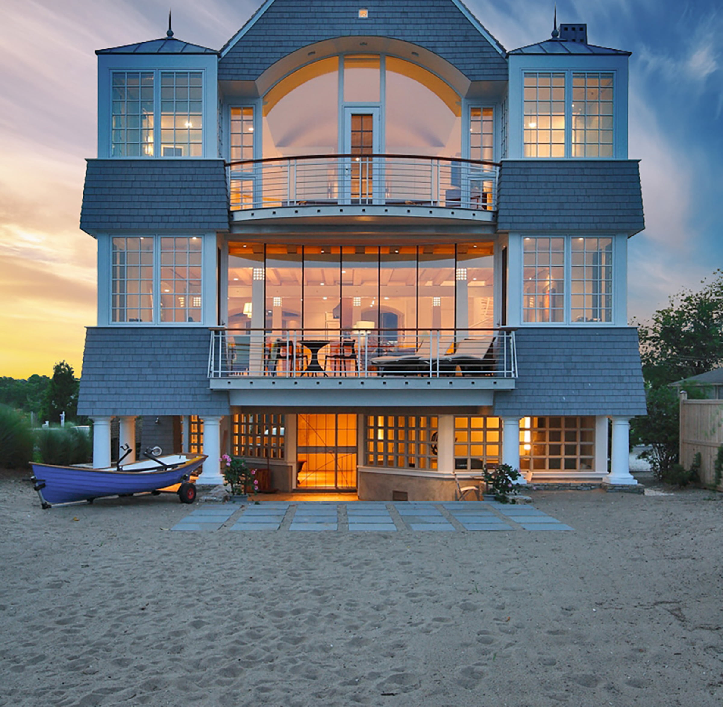 Exterior shot of beach house with floor-to-ceiling windows during sunset