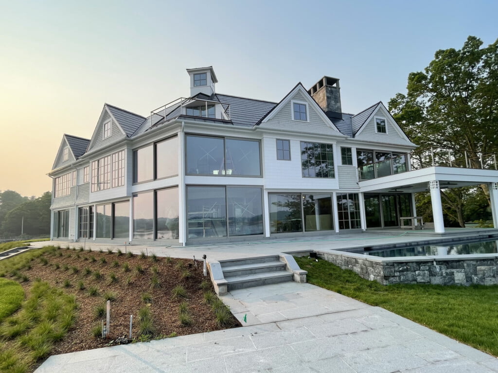 A white luxurious waterfront home with glass windows in Darien Conneticut